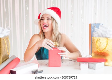 Pretty girl in Christmas hat laughing wrapping presents