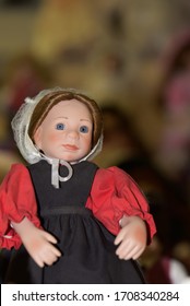 Pretty Girl Doll Dressed In Amish Clothing With A White Bonnet.  Background Is Blurred.