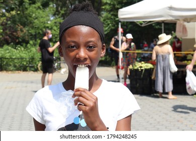 Pretty Girl eating Popsicle in outdoor marketplace on summer day - Powered by Shutterstock