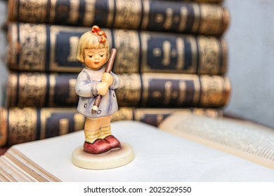 Pretty girl figurine on old book background. Student figurine on an book. First grader. Beginning of the school year