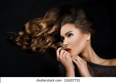 pretty girl with flowing hair and red lipstick turned at right with hand near the chin