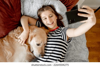 Pretty girl with golden retriever dog making selfie with smartphone in bed. Female teenager with purebred doggy pet and mobile cell phone doing photos - Powered by Shutterstock