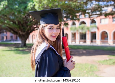 Pretty girl gratuate happily at campus with diploma holding in her hand