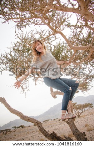 Pretty girl have fun on a tree in the desert in a day