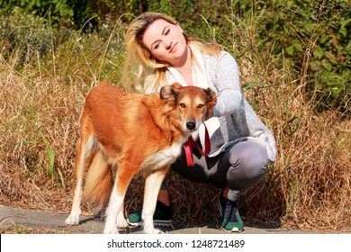 Pretty Girl With His Shetland Sheepdog Dog At Nature Park Outdoor Is Standing And Posing In Front Of Camera. Portrait Of Owner And Rough Collie Dog Enjoys, Resting And Petting Together On City Street.