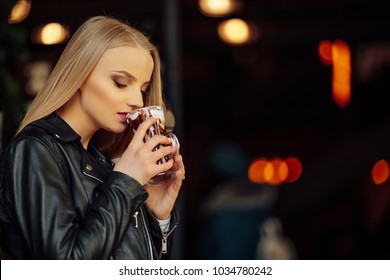 Pretty girl hold a cup of delicious coffee and waer glasses. Sun shine photo with girl drink her cappucino - Shutterstock ID 1034780242
