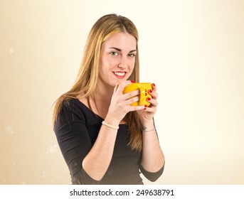 Pretty girl holding a cup of coffee over ocher background  - Shutterstock ID 249638791