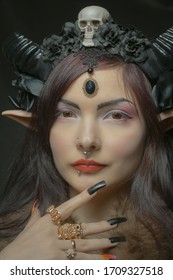 Pretty girl with horns and elvish ears posing over dark background