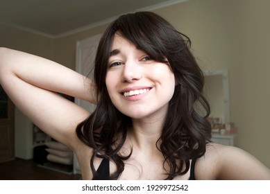 The pretty girl just woke up, no makeup. Smiling and looking at the camera. Natural look. Bedroom background.