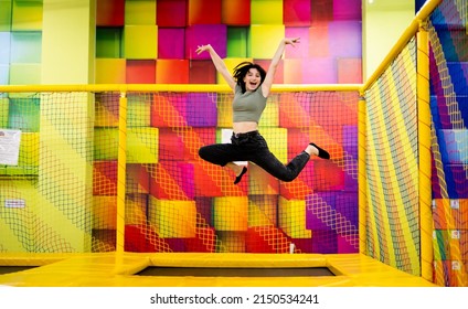 Pretty girl kid jumping on trampoline and happy at playground park. Female teenager in motion during active entertaiments