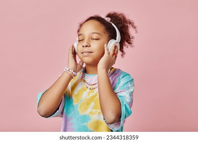 Pretty girl listening to healing or relaxation music in headphones while standing in front of camera and posing during photo session - Powered by Shutterstock