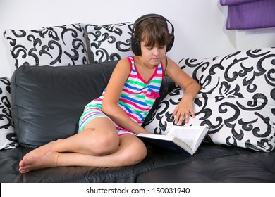 Pretty Girl Listening To Music With Headphones And Reading A Book