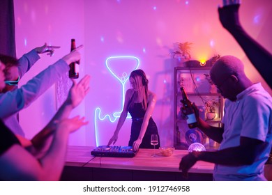 Pretty Girl With Long Blond Hair Standing By Counter With Turntables While Mixing Music For Disco Dancing And Enjoying At Home Party With Friends