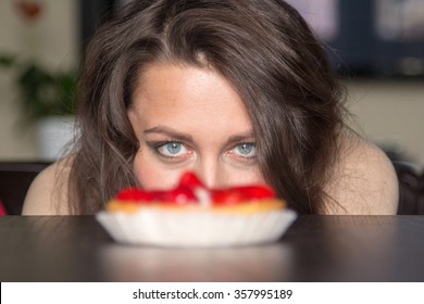 Pretty girl Looking to strawberry cake in living room