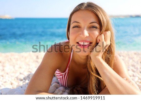 Pretty girl lying on pebbles beach. Summer holidays vacation concept.