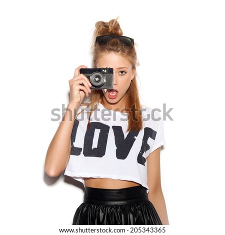 Pretty girl making photo using noname retro camera. White background, not isolated