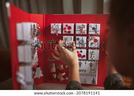 Pretty girl opens an original advent calendar like a book made of jewelry boxes and a binder, New Year craft, diy. Magic of moment, seasonal activity. Christmas miracle. Soft focus, depth of field