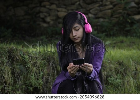 
a pretty girl with a phone in hand listening to music