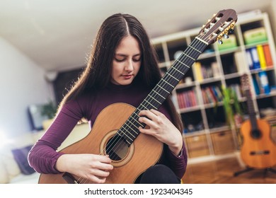 Pretty girl practicing some new sound on a guitar at home