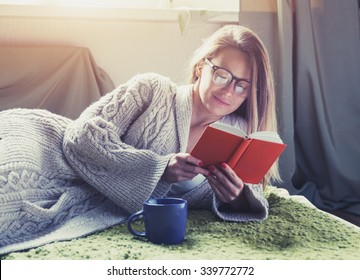 pretty girl reading book with coffee lying in bed