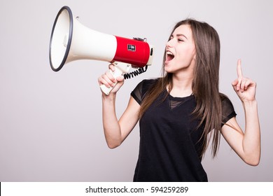 Pretty girl shouting into megaphone on copy space - Shutterstock ID 594259289