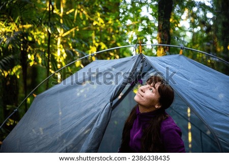 pretty girl sitting in a transparent tent and admiring unique rainforest at remote bush campground in lamington national park; gondwana rainforest in south east queensland, australia