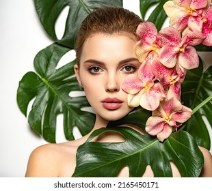 Pretty girl in Skin care beauty treatments concept. 
 Beautiful woman with green leave near face and body. Closeup girl's face with green leave. Model with pink tropical orchid near face.  - Shutterstock ID 2165450171