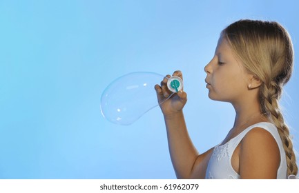 The pretty girl with soap bubbles. A blue background