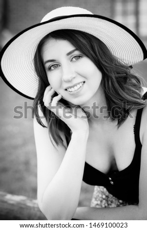 pretty girl in sun hat looking at camera, smiling, monochrome image