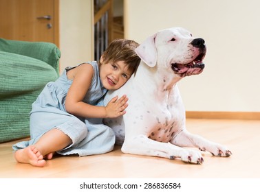 Pretty girl toddler on the floor with dogo Argentino