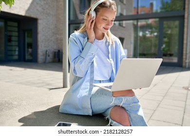 Pretty girl university student wearing headphones using laptop computer sitting on stairs outdoors in campus online learning, remote studying class, watching educational webinar course concept. - Shutterstock ID 2182128257