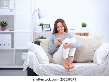 Pretty Girl Using Her Smartphone On  Couch At Home In The Living Room