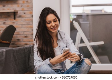 Pretty Girl Using Her Smartphone At Home, Reading Messages, Smiling