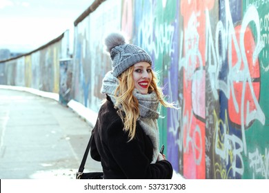 Pretty Girl Walking Next To The Berlin Wall Full With Graffiti 