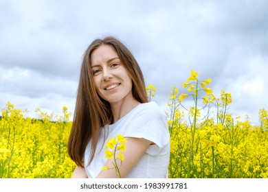 Pretty girl without makeup, with a wide smile in a field among yellow flowers