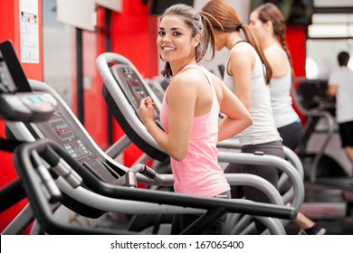 Pretty girl working out in a treadmill at the gym and smiling - Powered by Shutterstock