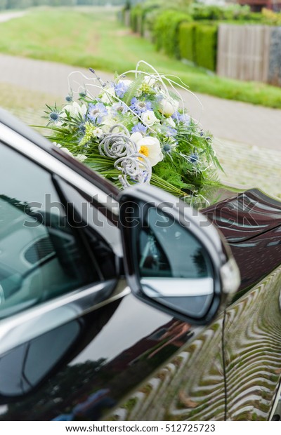 Pretty good wedding bouquet of various flowers on\
car. Purple and white.