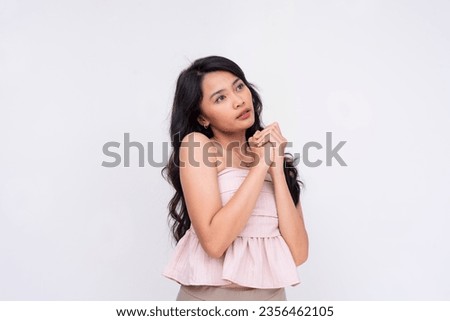 A pretty and grateful asian woman with clasped hands looking up and praying, looking for a fortunate result. Isolated on a white background.