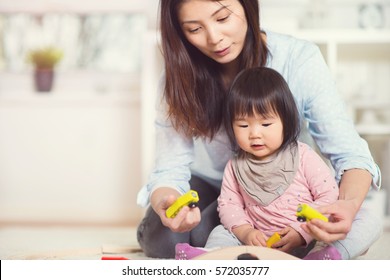 Pretty happy japanese mother play with her cute little toddler daughter at home