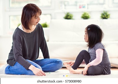 Pretty Happy Japanese Mother Play With Her Cute Little Daughter On Floor At Home