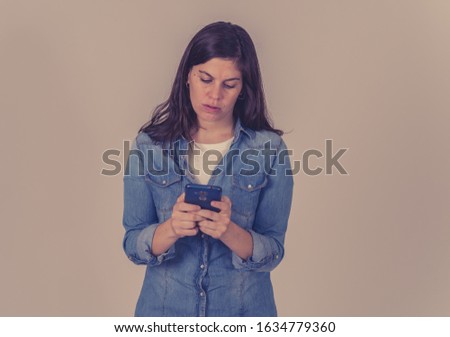 Pretty happy woman chatting online on smart phone and sharing text message using social media apps isolated on gray background. In People, lifestyle, online business and technology use.