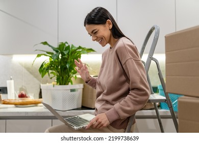 pretty happy woman moving in to new apartment with boxes in kitchen using laptop - Powered by Shutterstock