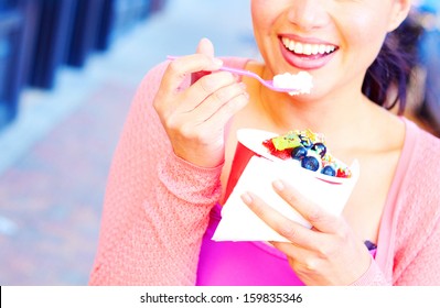 Pretty Happy Young Pretty Mixed Race Female Eating Frozen Yogurt While Looking Away. Horizontal Shot.