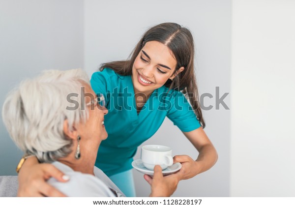 Pretty helpful\
carer talking with female patient. Health visitor and a senior\
woman during home visit. Supportive senior care assistant and\
smiling older woman in nursing\
home