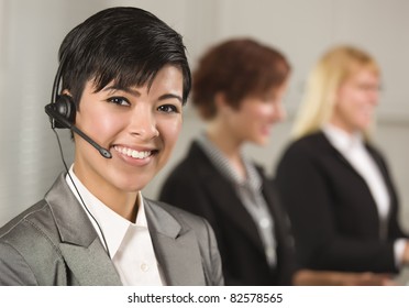 Pretty Hispanic Businesswoman With Colleagues Behind In An Office Setting.