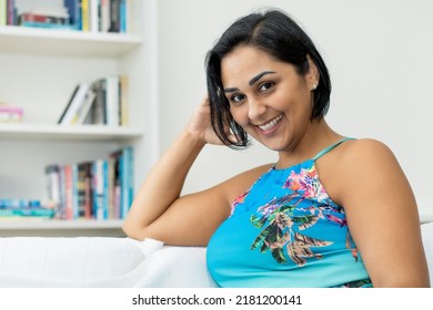 Pretty Hispanic Mature Adult Woman In Colorful Dress Indoors At Home