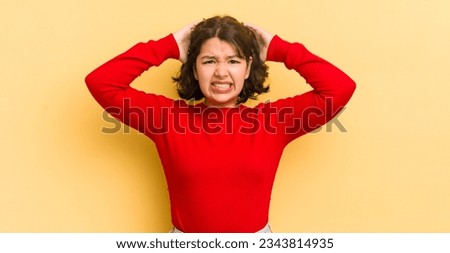 pretty hispanic woman feeling stressed, worried, anxious or scared, with hands on head, panicking at mistake
