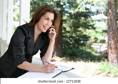 A Pretty Hispanic Woman On The Phone On Her Home Porch