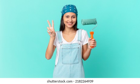 Pretty Hispanic Woman Smiling And Looking Friendly, Showing Number Two. Painting Home Concept