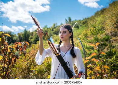 pretty hunter girl shooting bow and arrow  in the grassland 